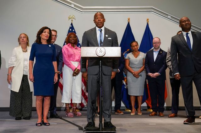 Mayor Eric Adams at the podium during a press conference pushing for New York City to host the Democratic National Convention. On the left is Gov. Kathy Hochul. On the right is DNC Chair Jamie Harrison.